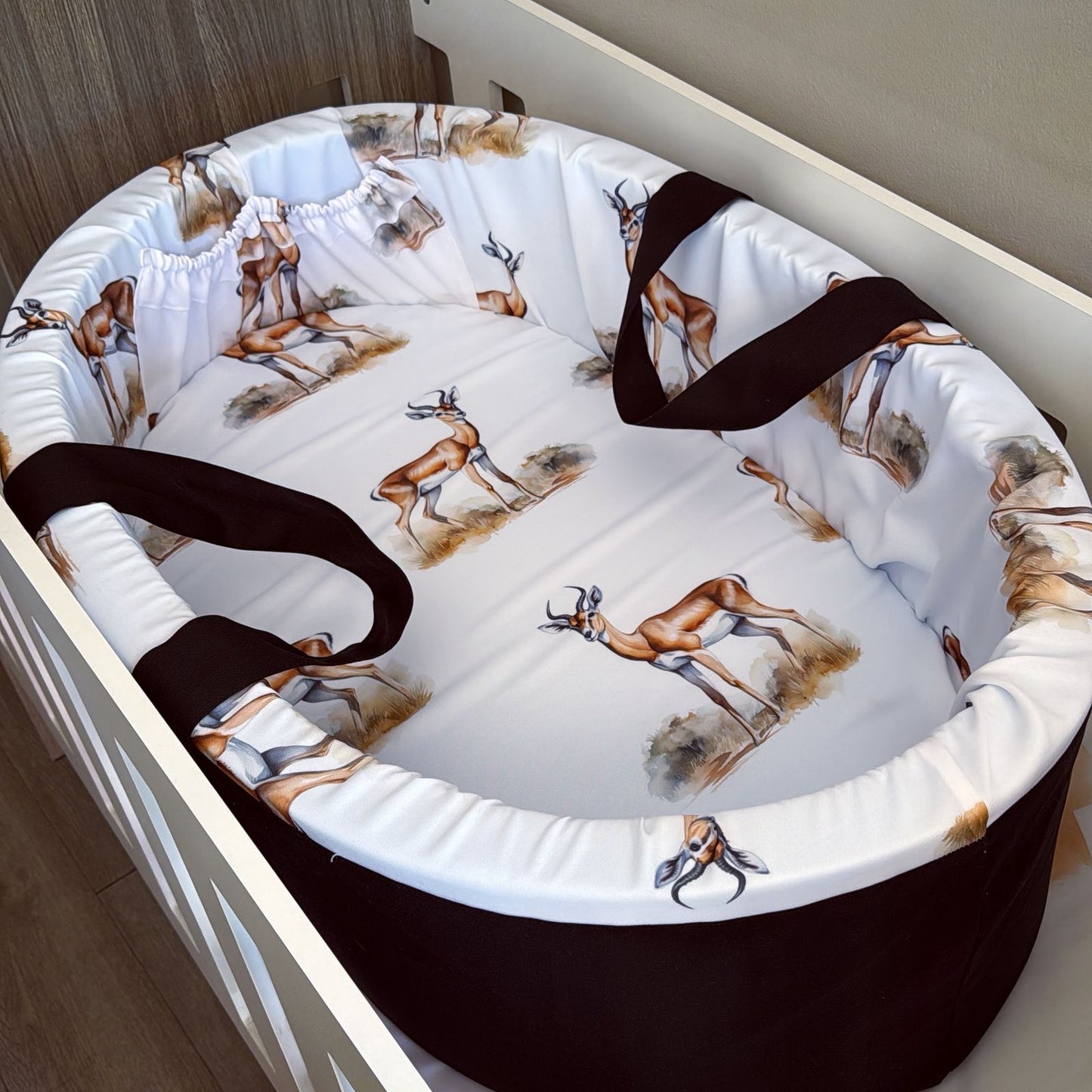 Baby crib with deer patterned bedding and black straps