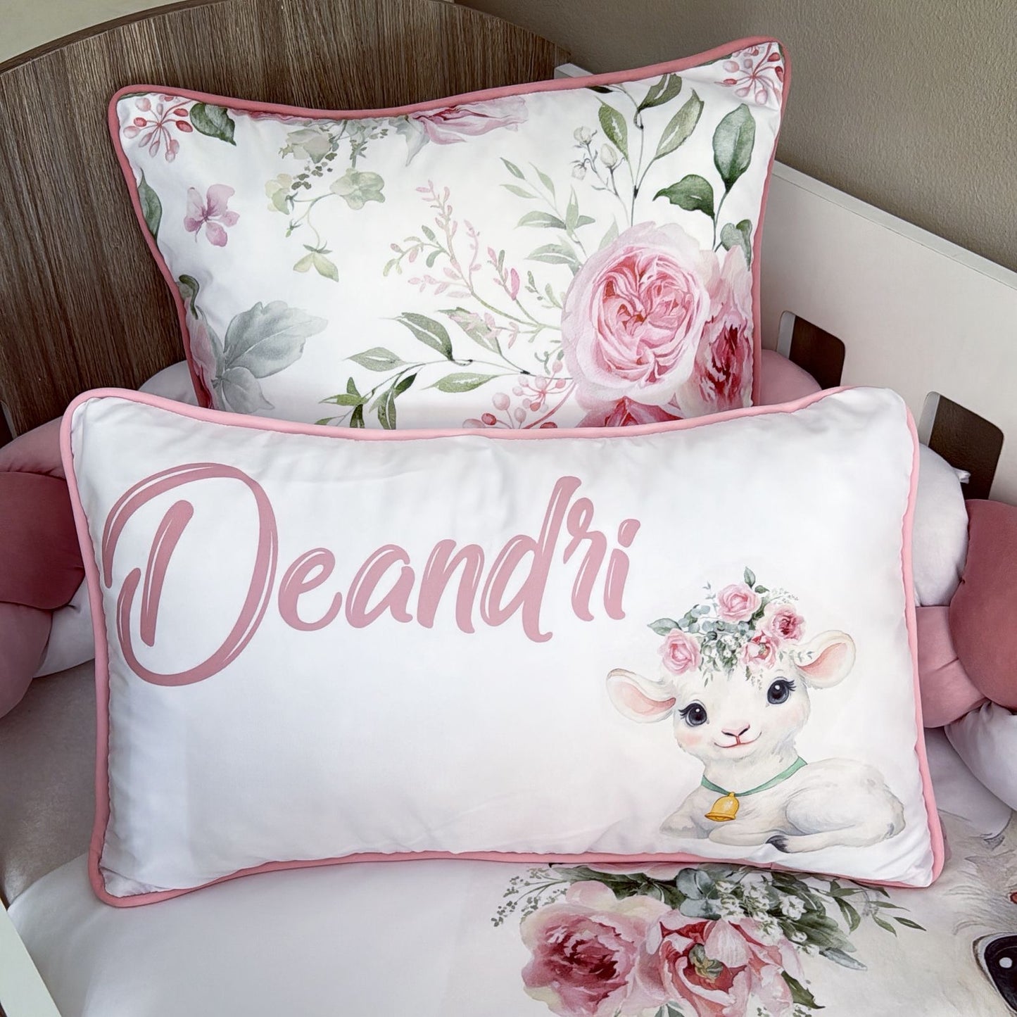 Decorative pillow with floral design and 'Deandri' branding on a bed.