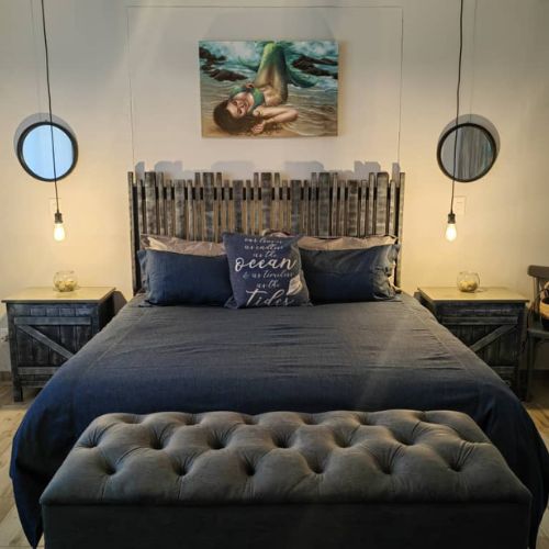 Bedroom with wooden headboard, blue bedding, and decorative pillows.