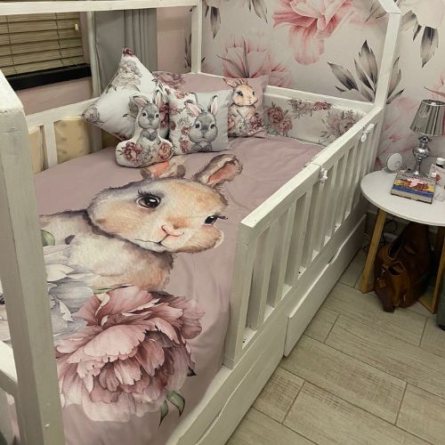 Children's crib with floral and animal-themed bedding and pillows.