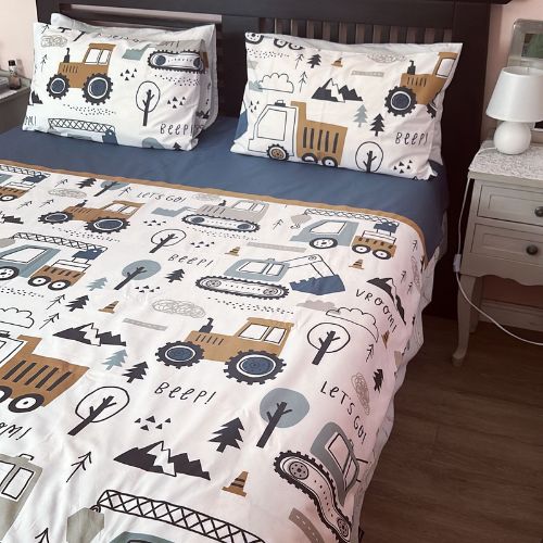 Children's bedding set with truck and nature pattern on a bed in a bedroom.