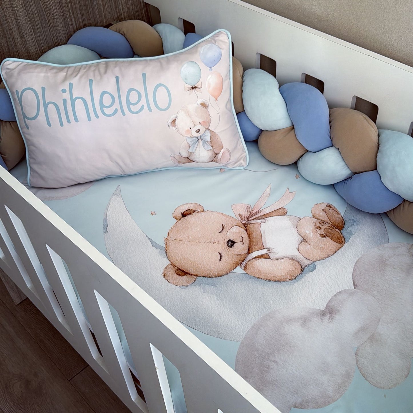 Crib with teddy bear, pillow, and decorative elements in a nursery setting
