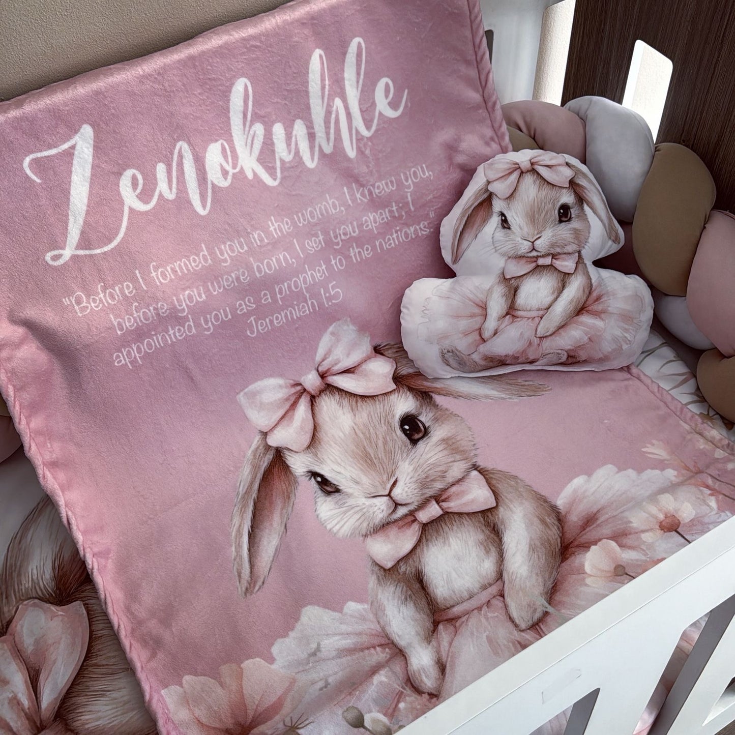 Pink pillow with bunny design and text on a bed