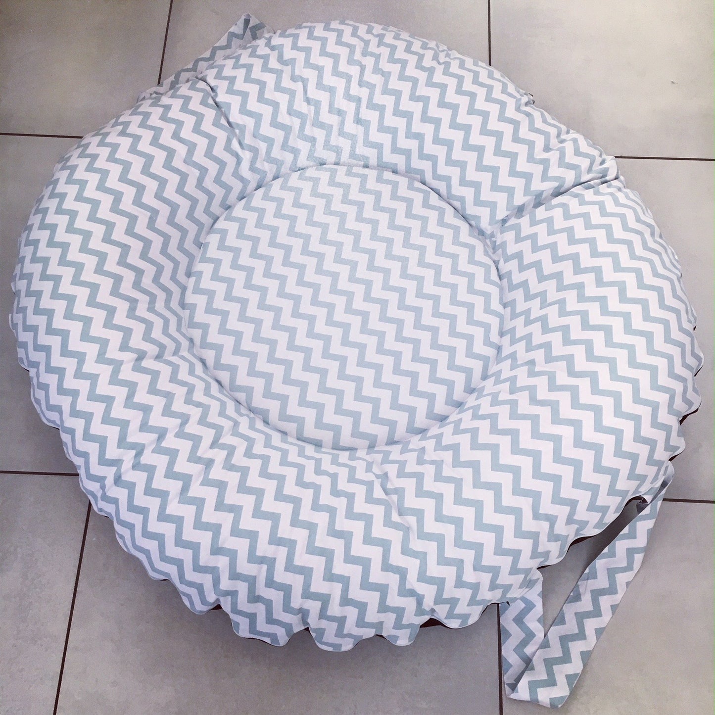 Round cushion with chevron pattern on a tiled floor