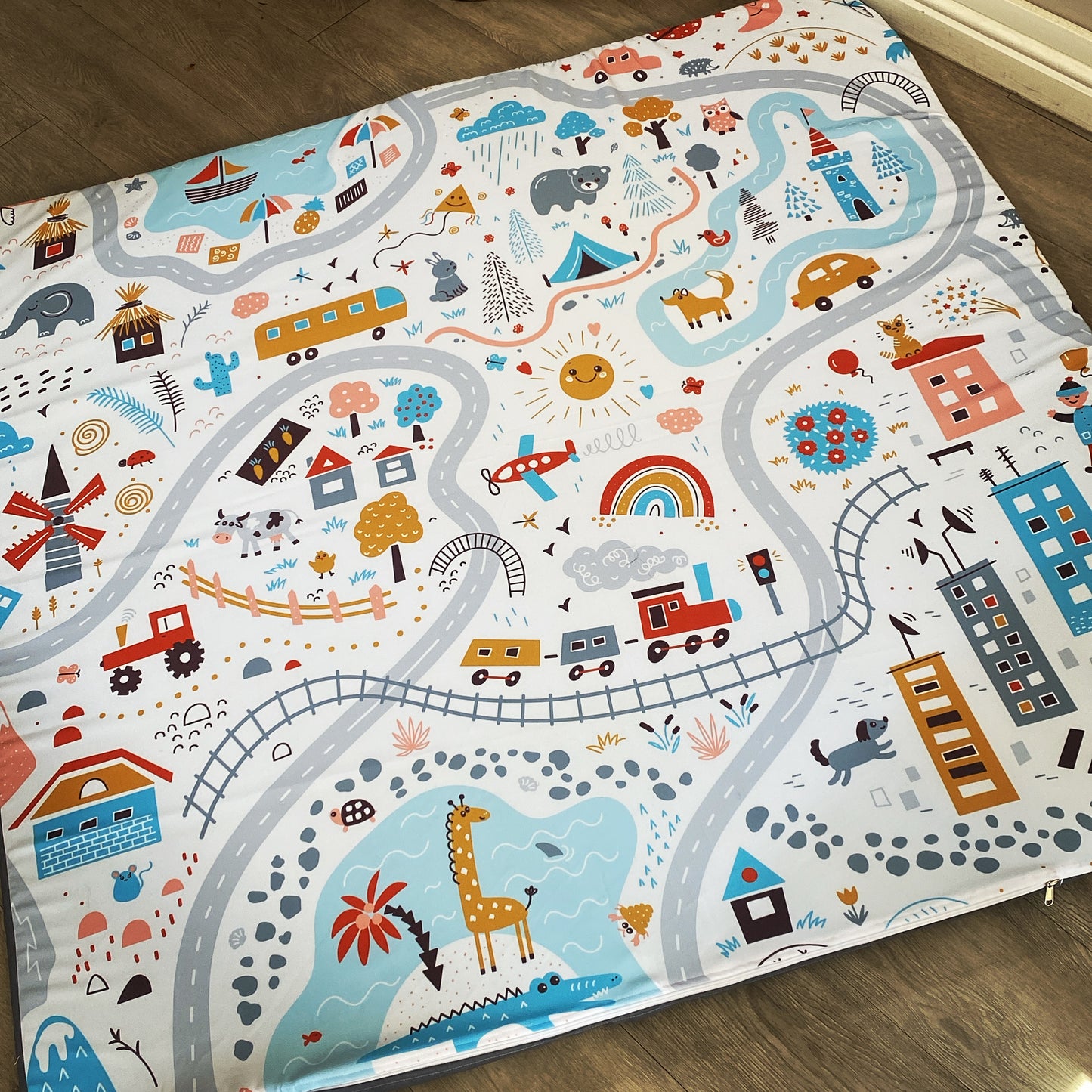 A foam playmat with a colorful ocean and transportation theme, featuring various cartoonish illustrations such as animals, vehicles, and buildings.
