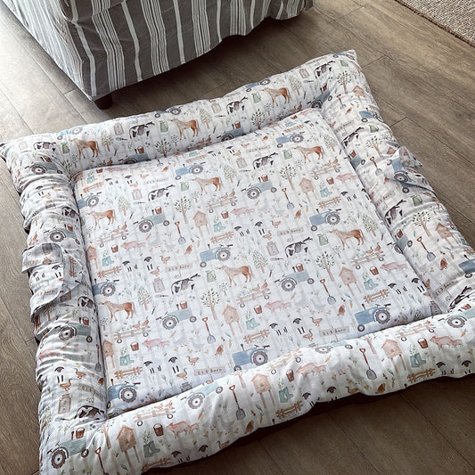 Patterned doughnut bed on a wooden floor with a striped rug in the background