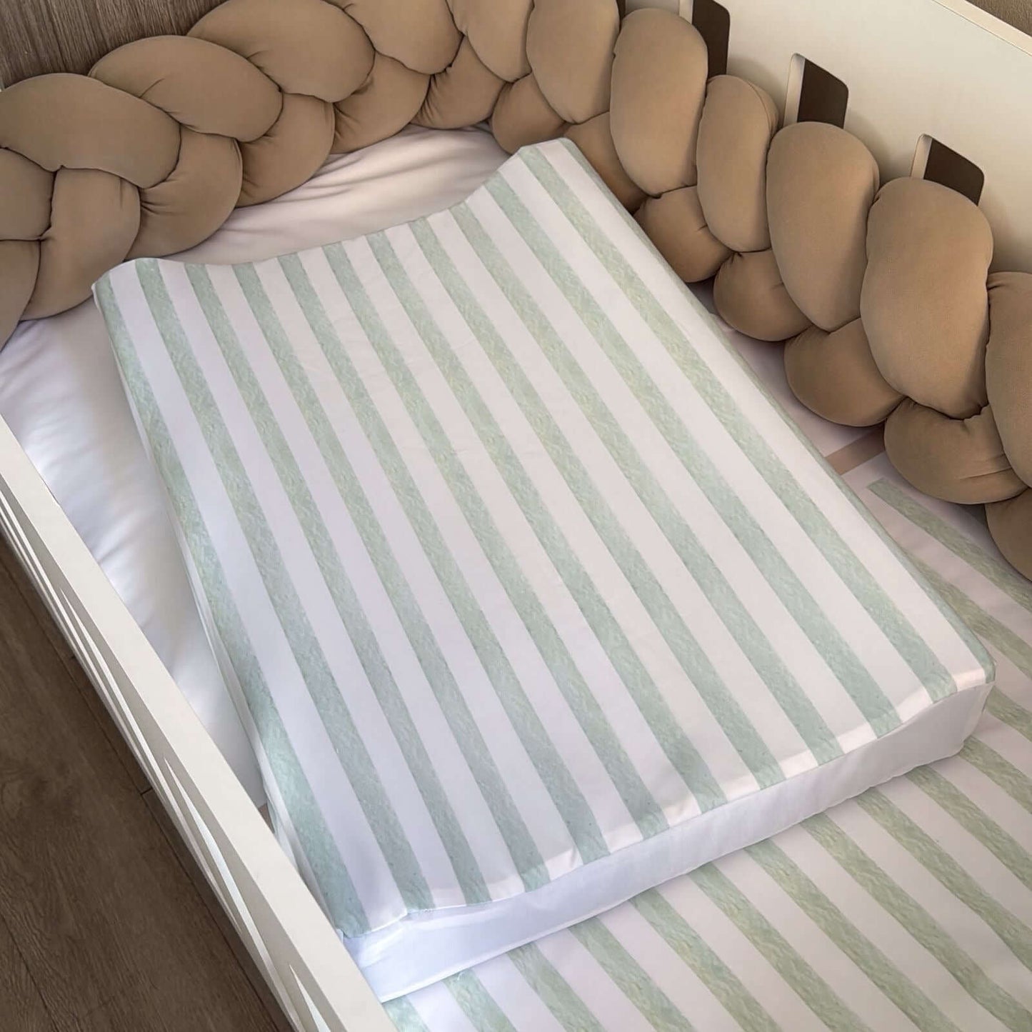 Striped crib changing station on a crib with a braided headboard