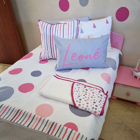 Children's bed with polka dot bedding and colorful pillows in a bedroom setting.
