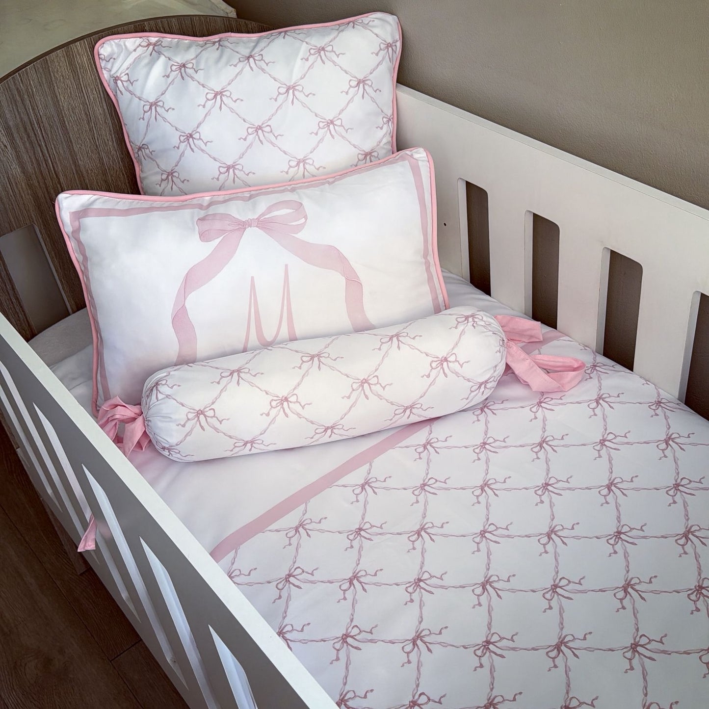 Children's bed with pink and white patterned bedding and pillows.
