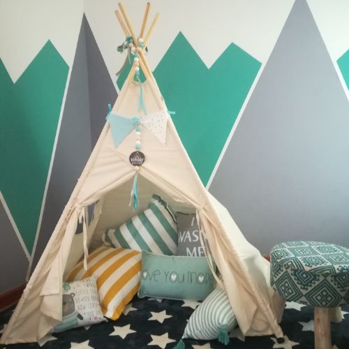 Children's teepee with pillows against a wall with geometric patterns