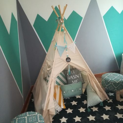 Children's teepee in a room with geometric wall design and star-patterned floor.