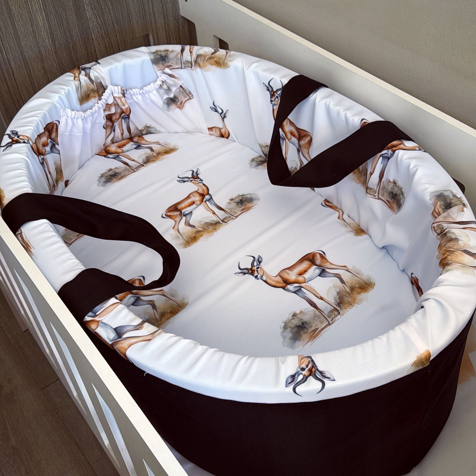 Baby crib with deer patterned bedding and black straps