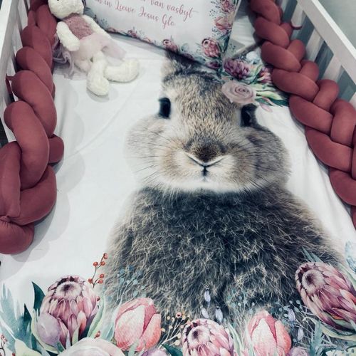 Floral-patterned blanket with a rabbit design on a crib