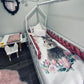 Children's room with a bed featuring a floral and animal design, pink accents, and small table with chair.