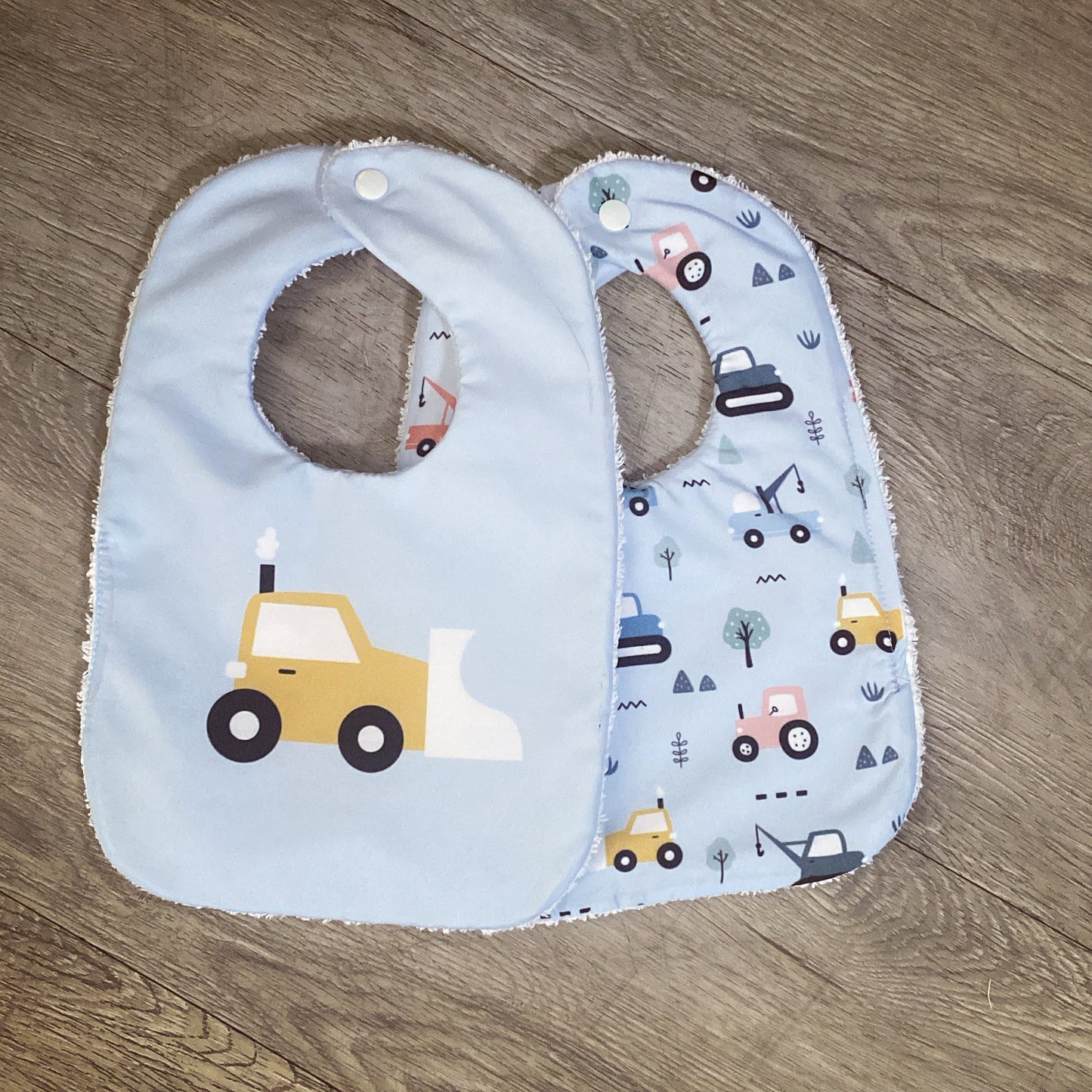Baby bib with construction vehicle pattern on a wooden surface