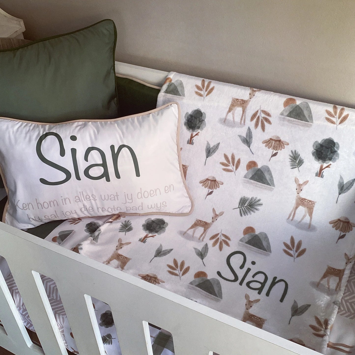 Crib with patterned sheet and pillow with 'Sian' printed on it