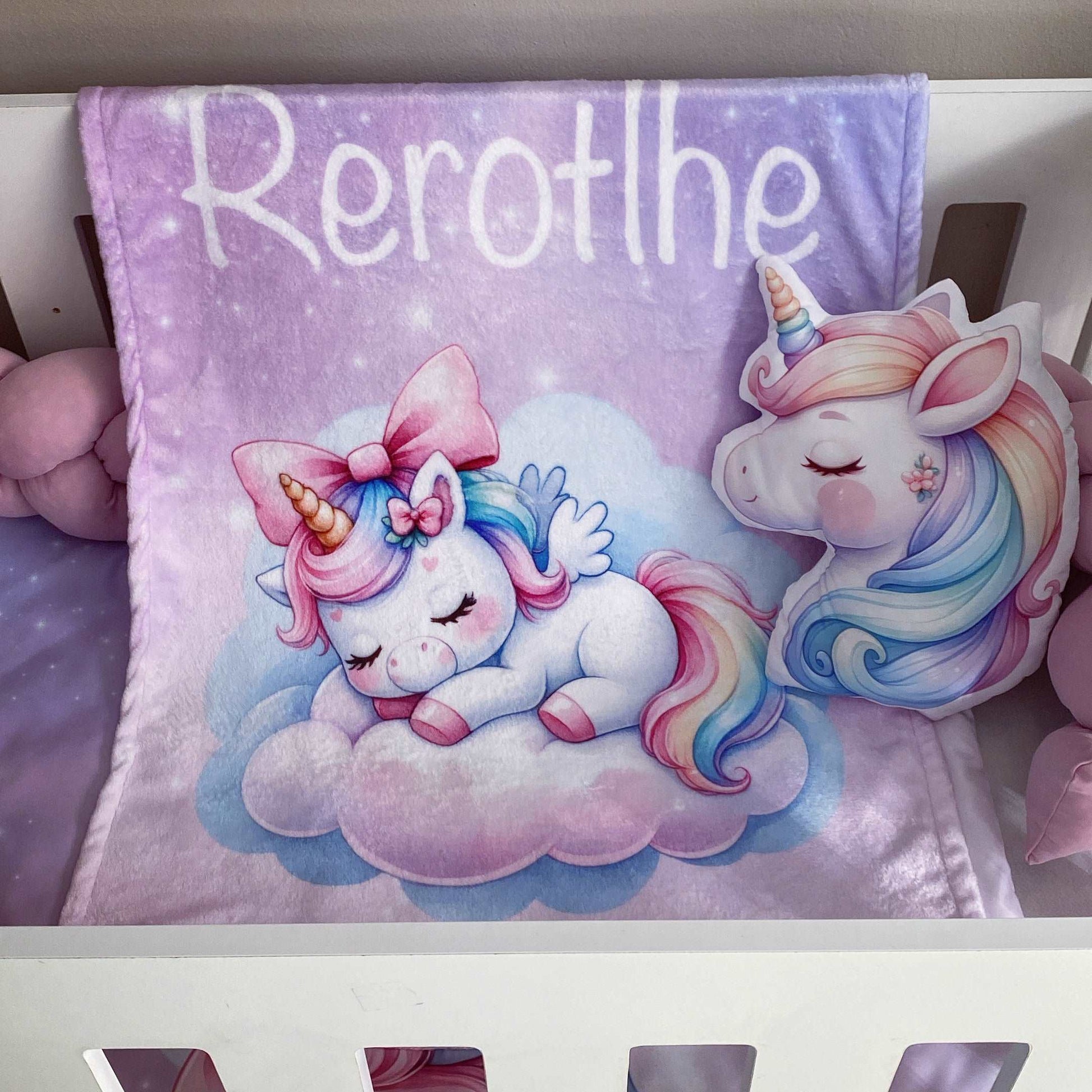 Children's blanket with cartoon unicorns and the name 'Rerotlhe' on a white surface.