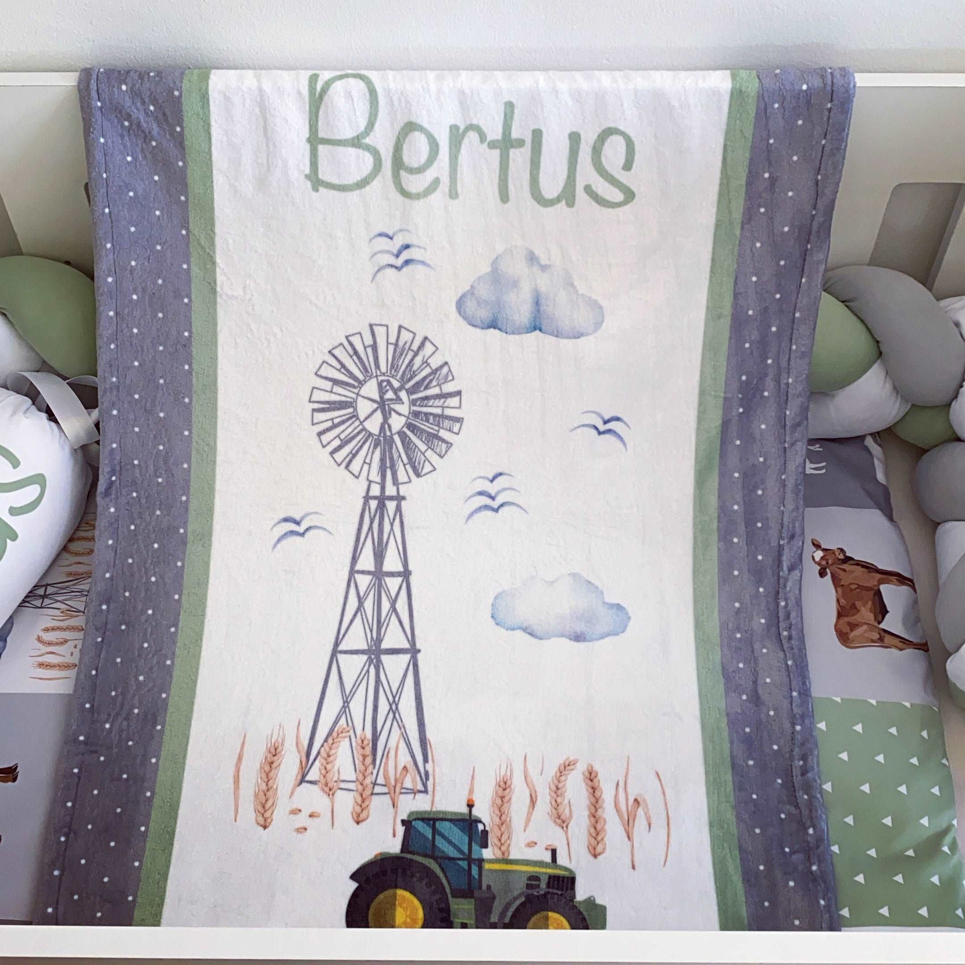 Blanket with a windmill, tractor, and clouds design on a white background.