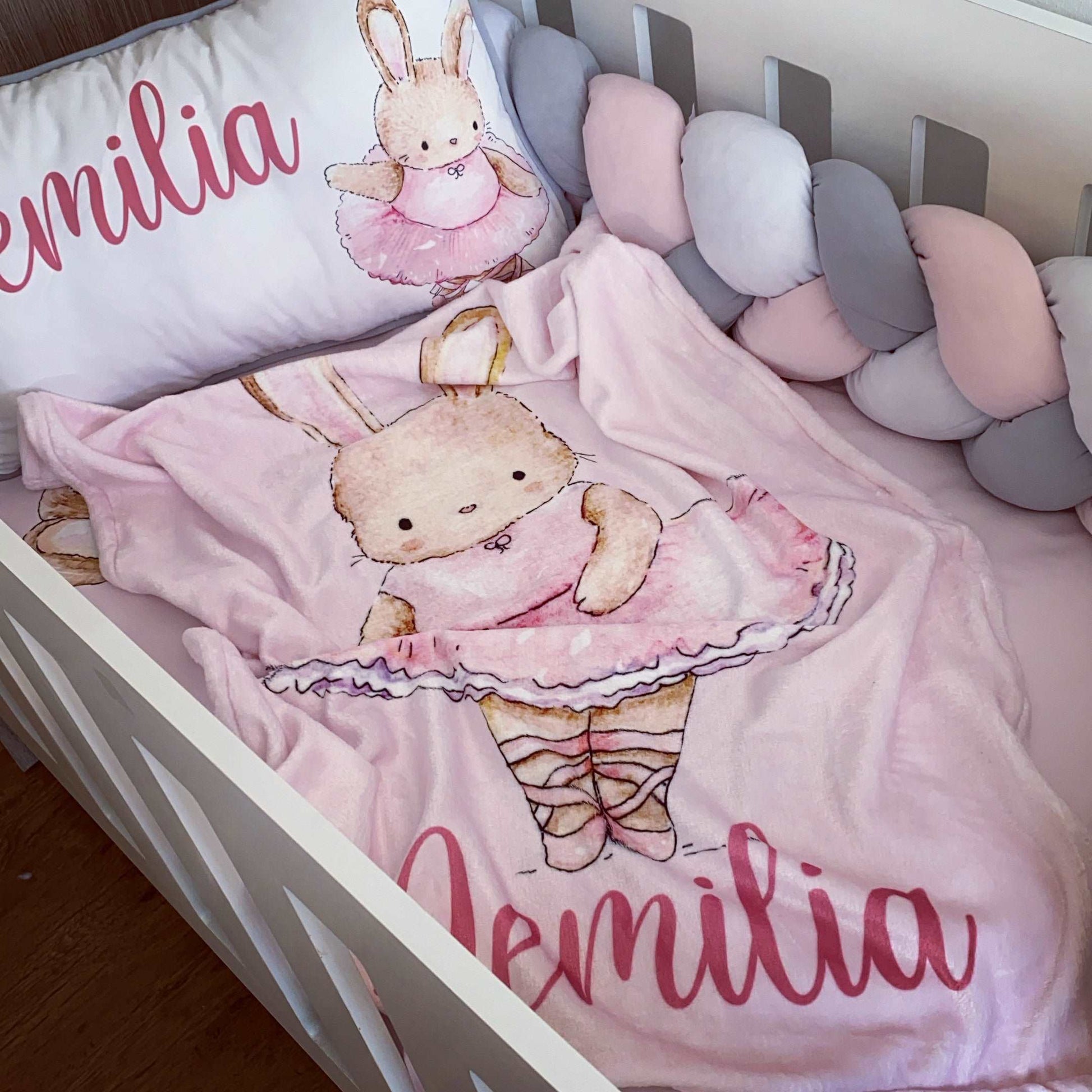 Children's bedding set with a bunny design and 'Emilia' branding on a crib.