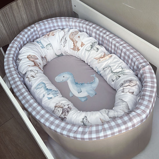 Baby crib with dinosaur-themed bedding in a checkered crib bumper.