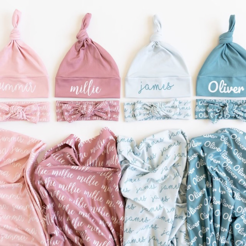 Set of baby hats and blankets with personalized names in pink, blue, and white.