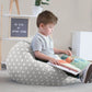 Child sitting on a star-patterned bean bag reading a book in a cozy room. | Baby Essentials | All Baby Products | Soft Spot Kids | South Africa