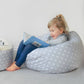 Child sitting on a star-patterned bean bag reading a book in a cozy room. | Baby Essentials | All Baby Products | Soft Spot Kids | South Africa