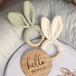 Two knitted bunny ear rings on a white surface with a wooden disc that says 'hello WORLD'. | Baby Essentials | All Baby Products | Soft Spot Kids | South Africa