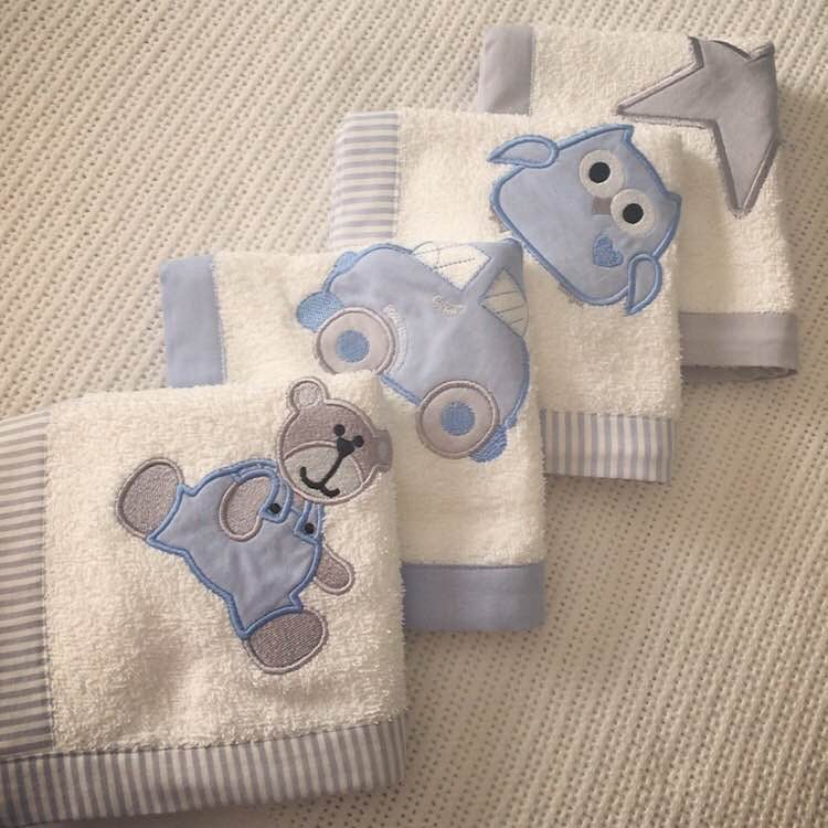 Set of baby Burp Cloths towels with animal appliqués on a textured surface