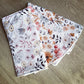 Two floral-patterned Burp Cloths fabric swatches on a wooden surface | Baby Essentials | All Baby Products | Soft Spot Kids | South Africa