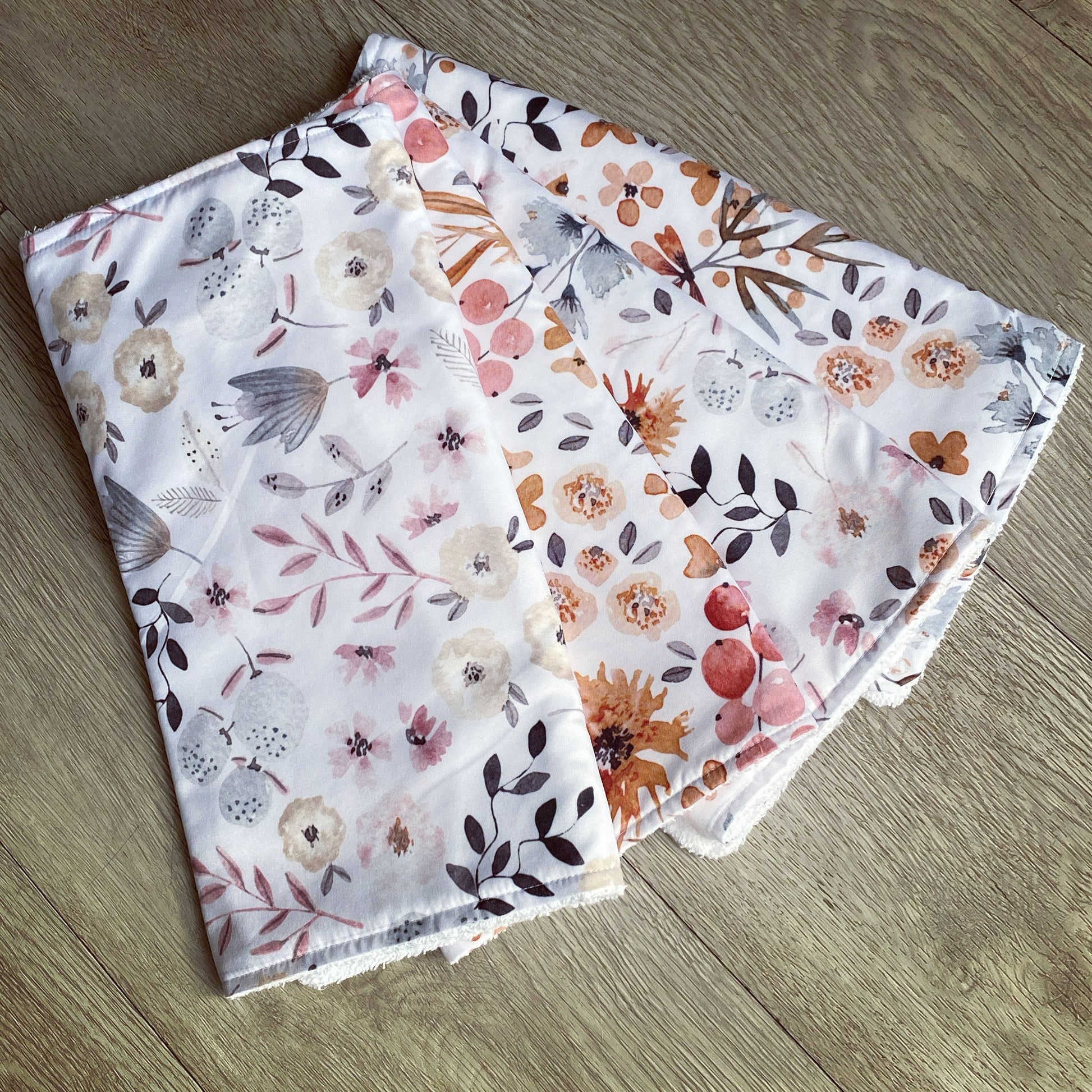 Two floral-patterned Burp Cloths fabric swatches on a wooden surface