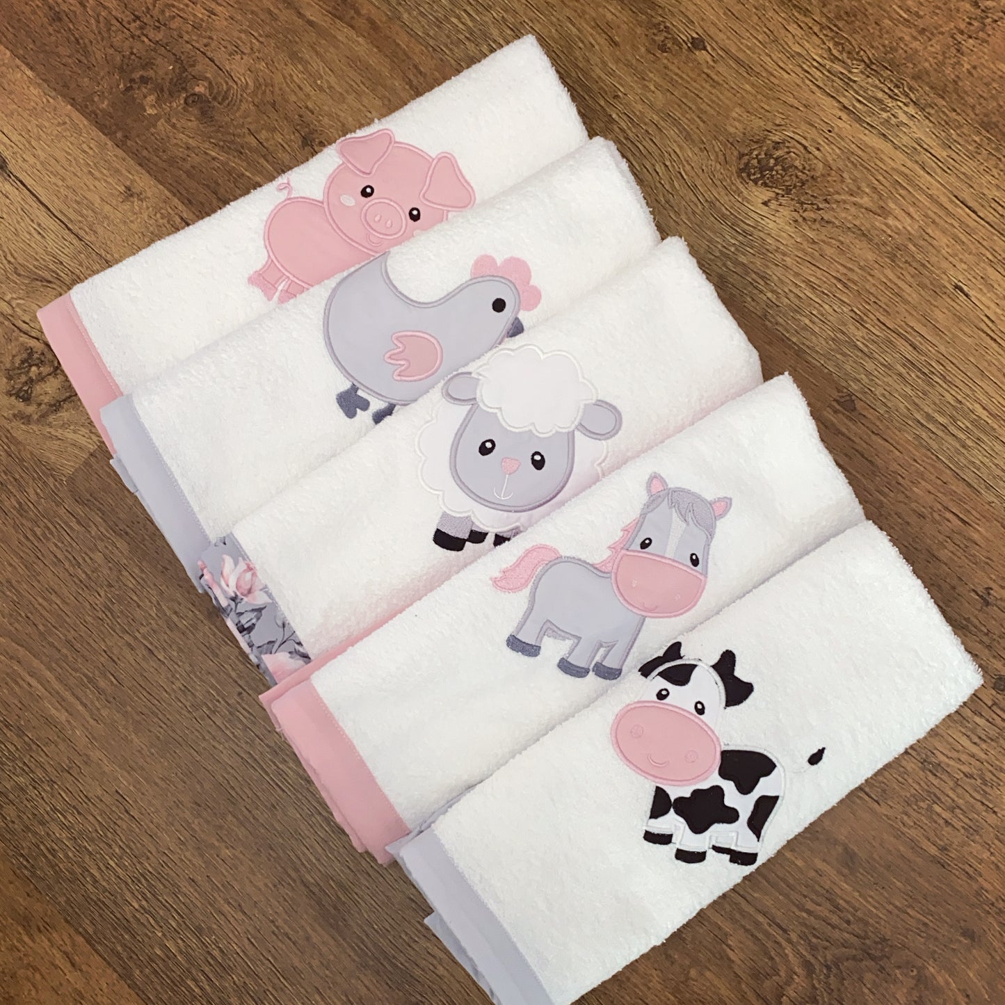 Set of baby Burpcloths - Pink Farm 03with animal illustrations on a wooden surface