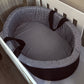 An oval carry cot with a black and white gingham check pattern and dark brown trim and handles, shown placed inside a white crib. | Baby Carry Cots | Portable Baby Beds | Soft Spot Kids | South Africa