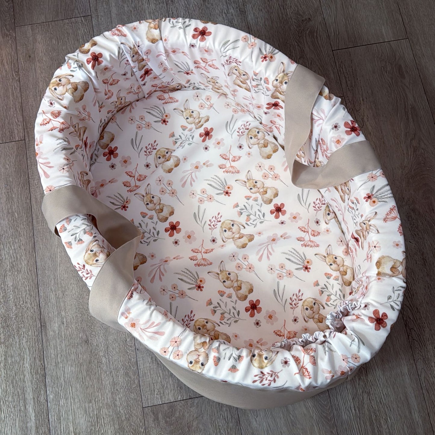 Floral-patterned baby carry cot on a wooden floor