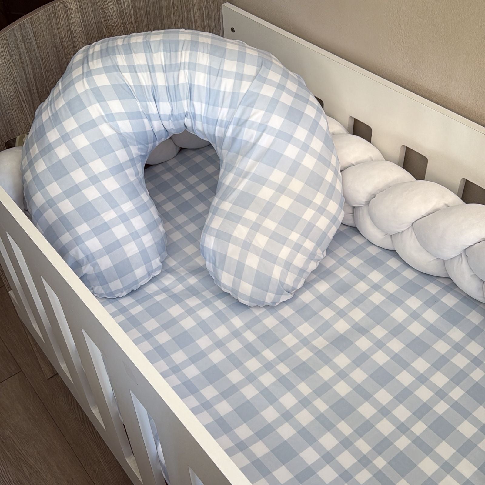 Plaid-patterned pillow in a crib with checkered sheet