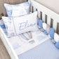 A baby bedding set styled in a white wooden crib, featuring a white sheet with blue stripes, a matching blue and white hot air balloon print, a personalized white pillow with the name 'Elian' in blue script, and coordinating pillows and a blue-and-white ball crib bumper. | All Nursery Sets | Baby Bedding Sets South Africa | Soft Spot Kids | South Africa