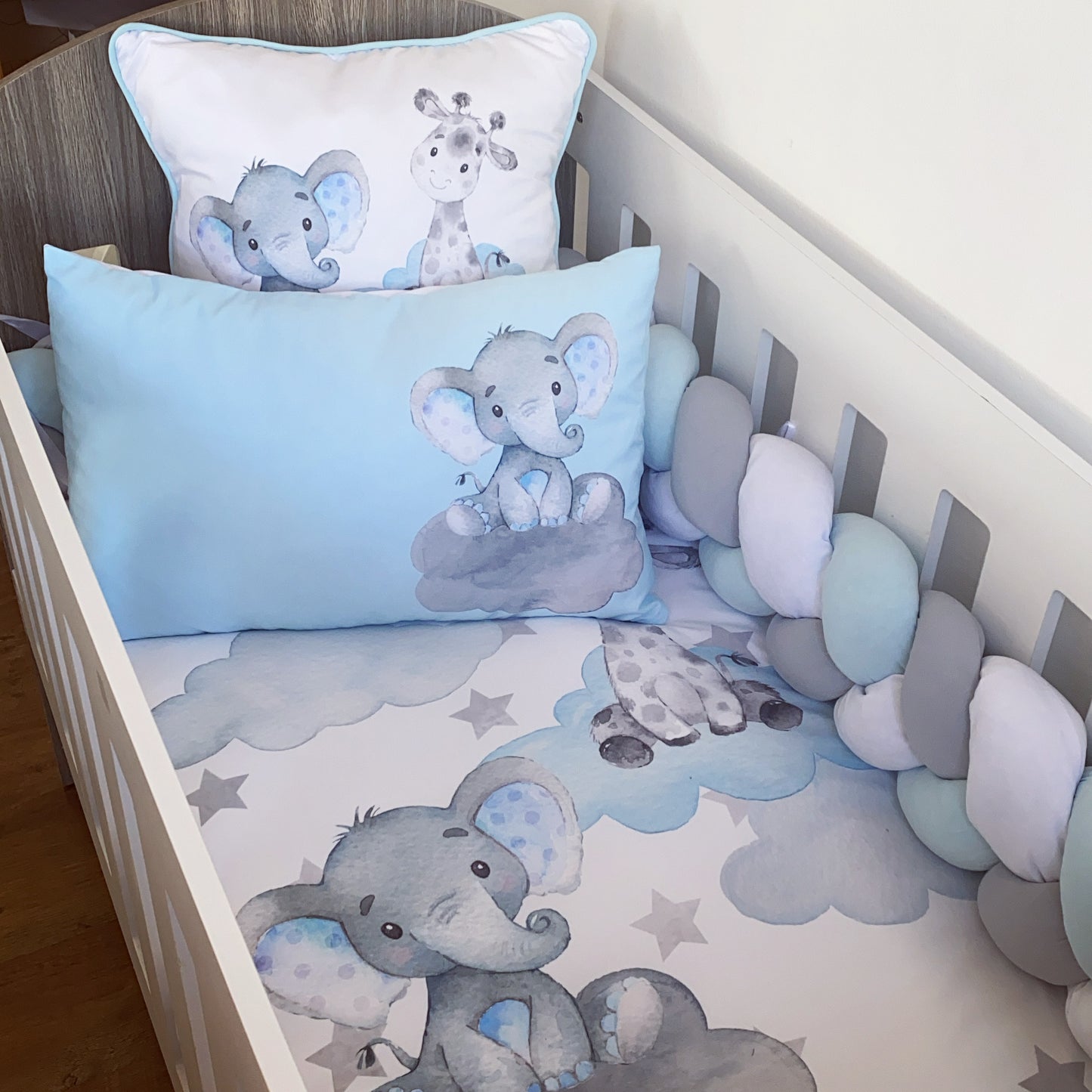 Baby crib with elephant-themed bedding and pillows