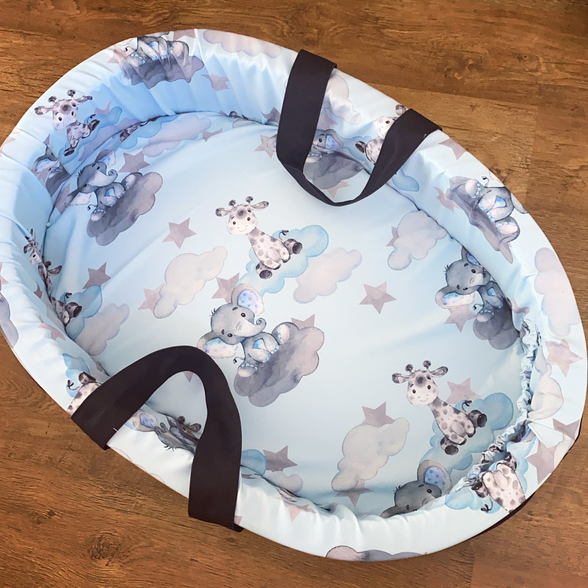 Baby carry cot with animal pattern on a wooden surface