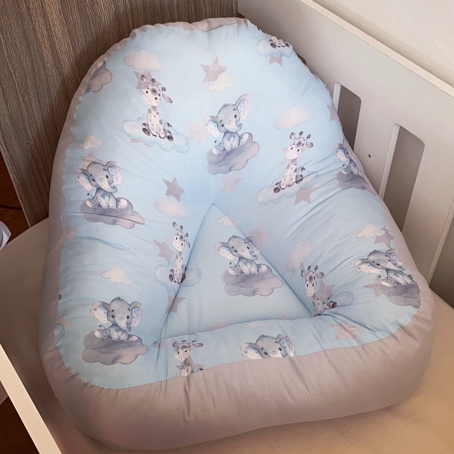 Baby lounger with elephant safari pattern in a crib