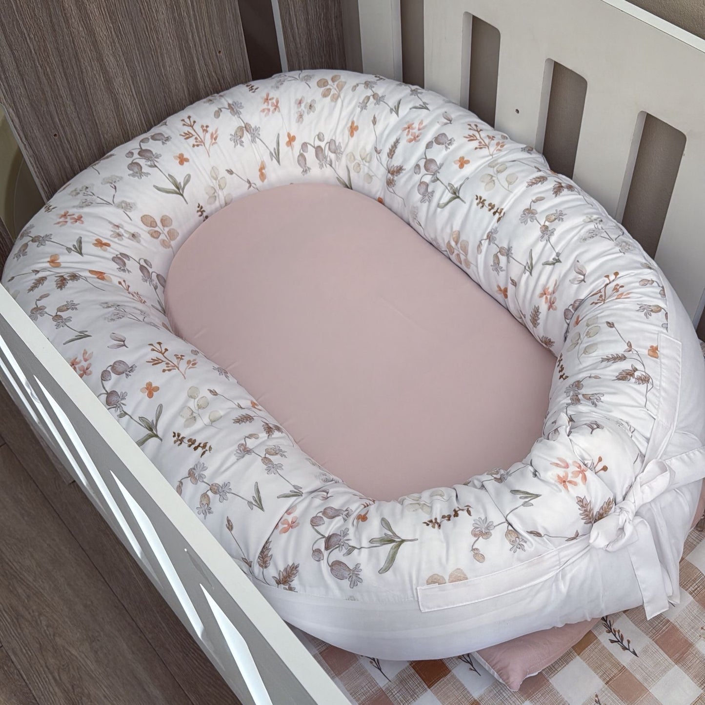 Baby nest with floral pattern inside a crib