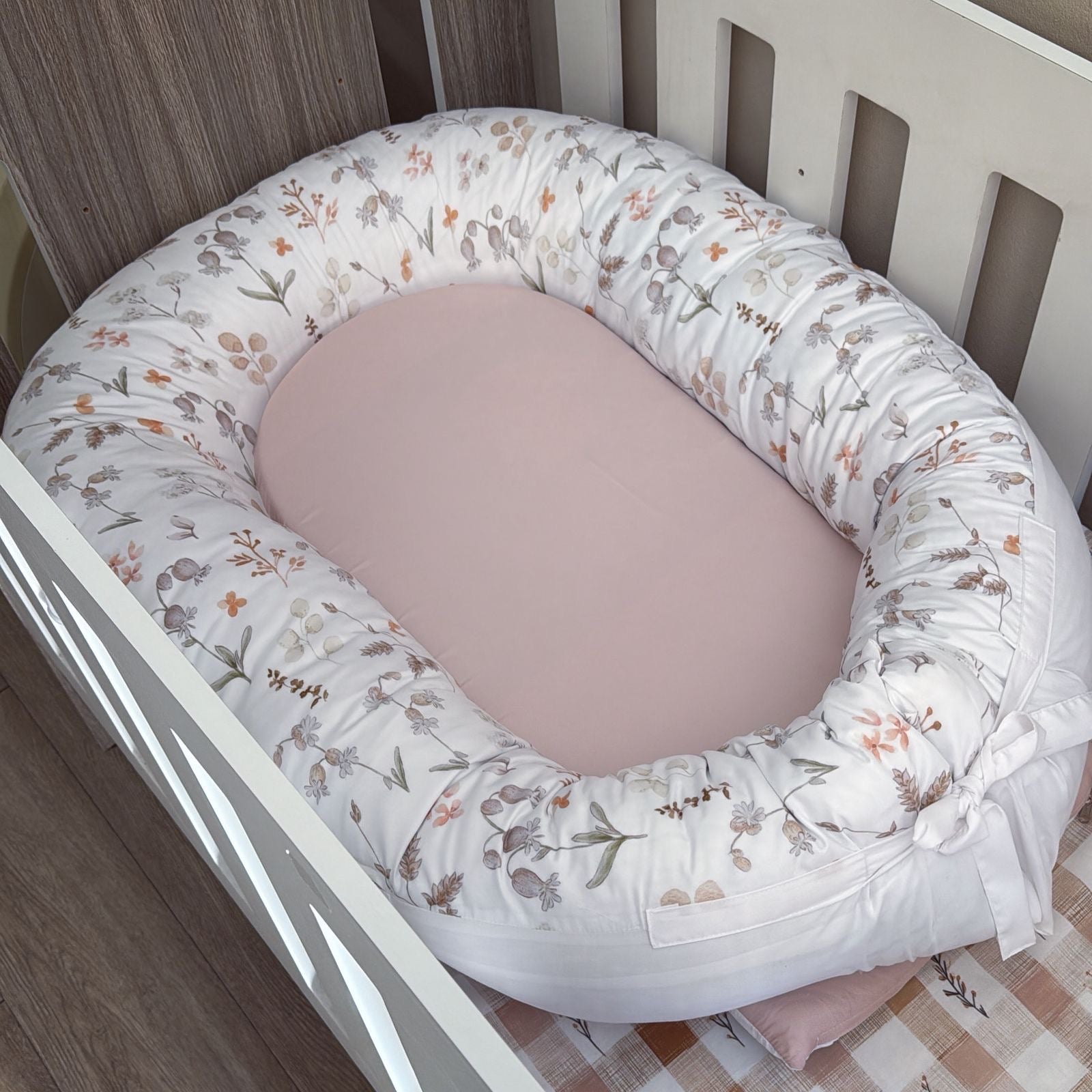 Baby nest with floral pattern inside a crib