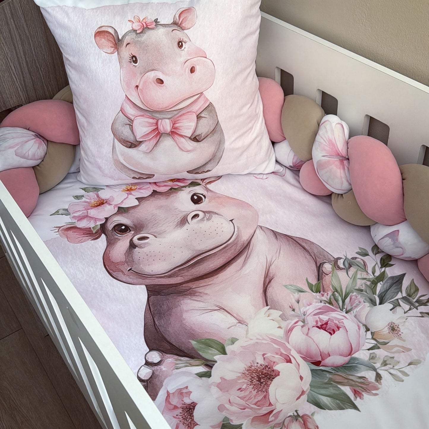 Children's bedding set with a pink hippo design on a crib