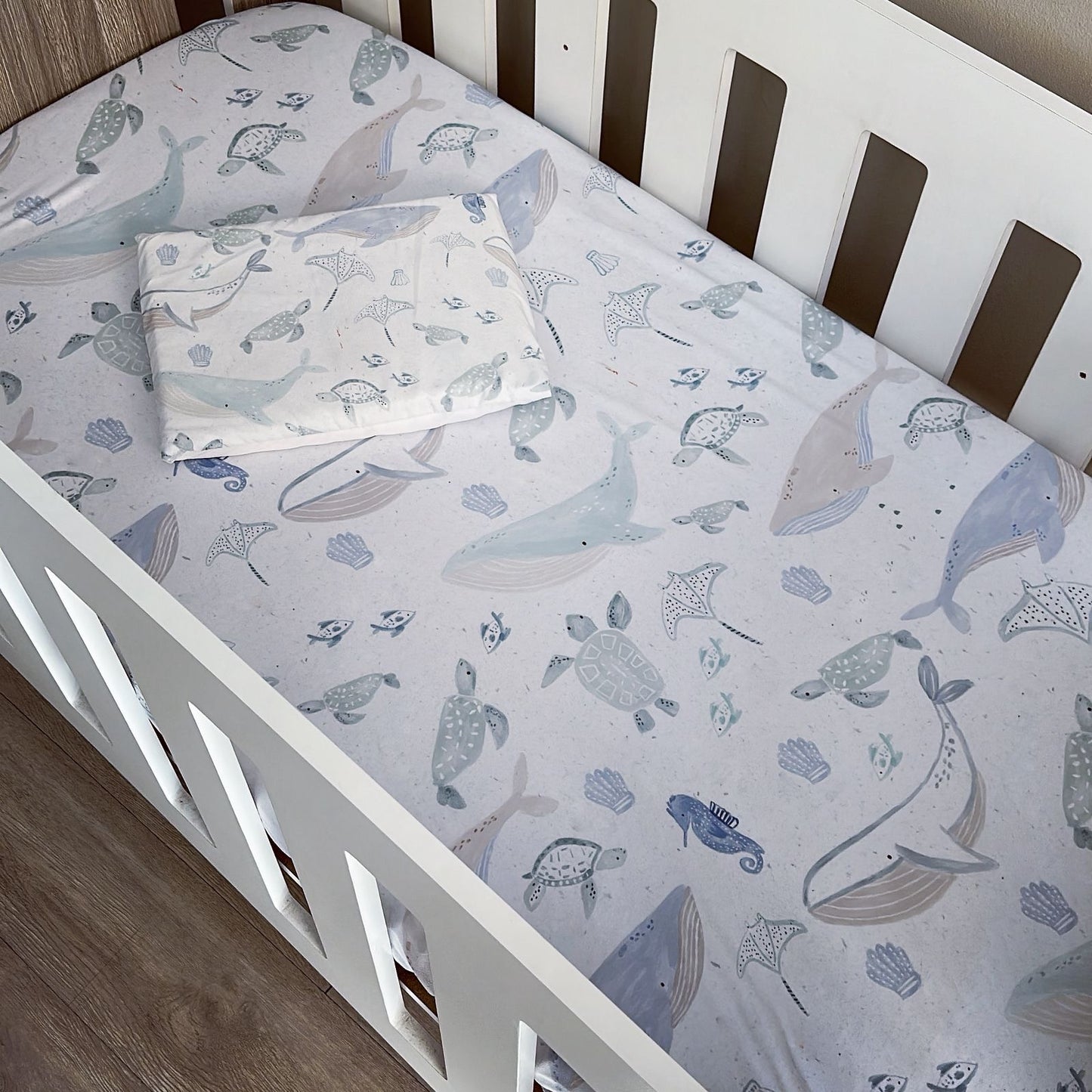 Crib with whale and turtle patterned sheet and pillow