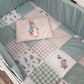 A baby bedding set in a crib, featuring a patchwork quilt in sage green, beige, and white with Peter Rabbit illustrations, and a matching pillow with a central Peter Rabbit print. | All Nursery Sets | Baby Bedding Sets South Africa | Soft Spot Kids | South Africa