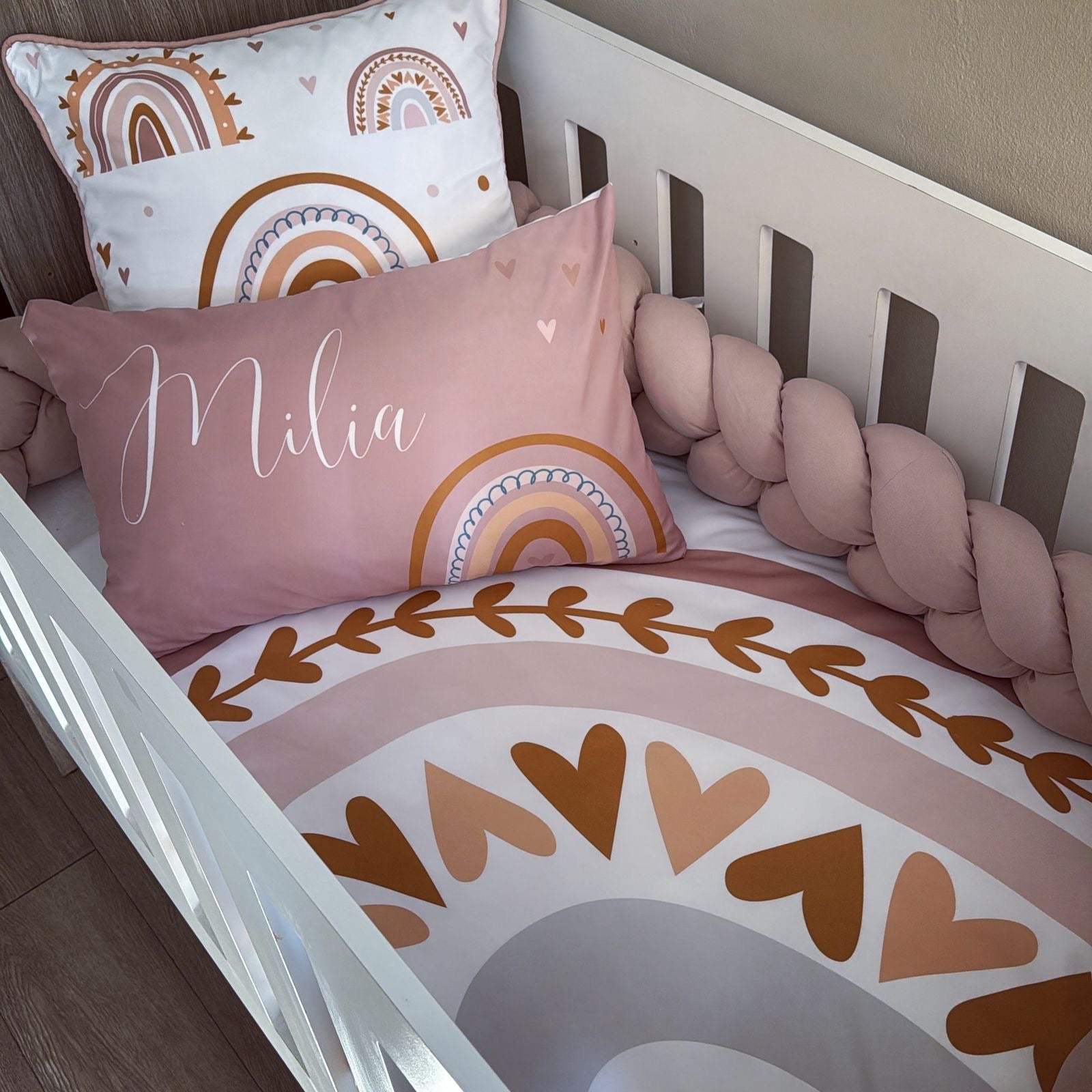 Crib with pink pillow and rainbow-patterned bedding
