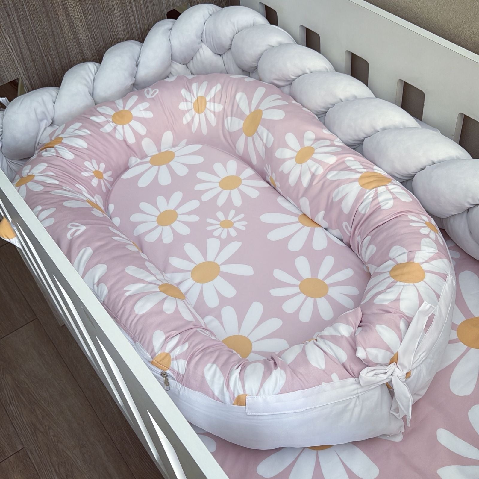 Baby nest with daisy pattern inside a crib