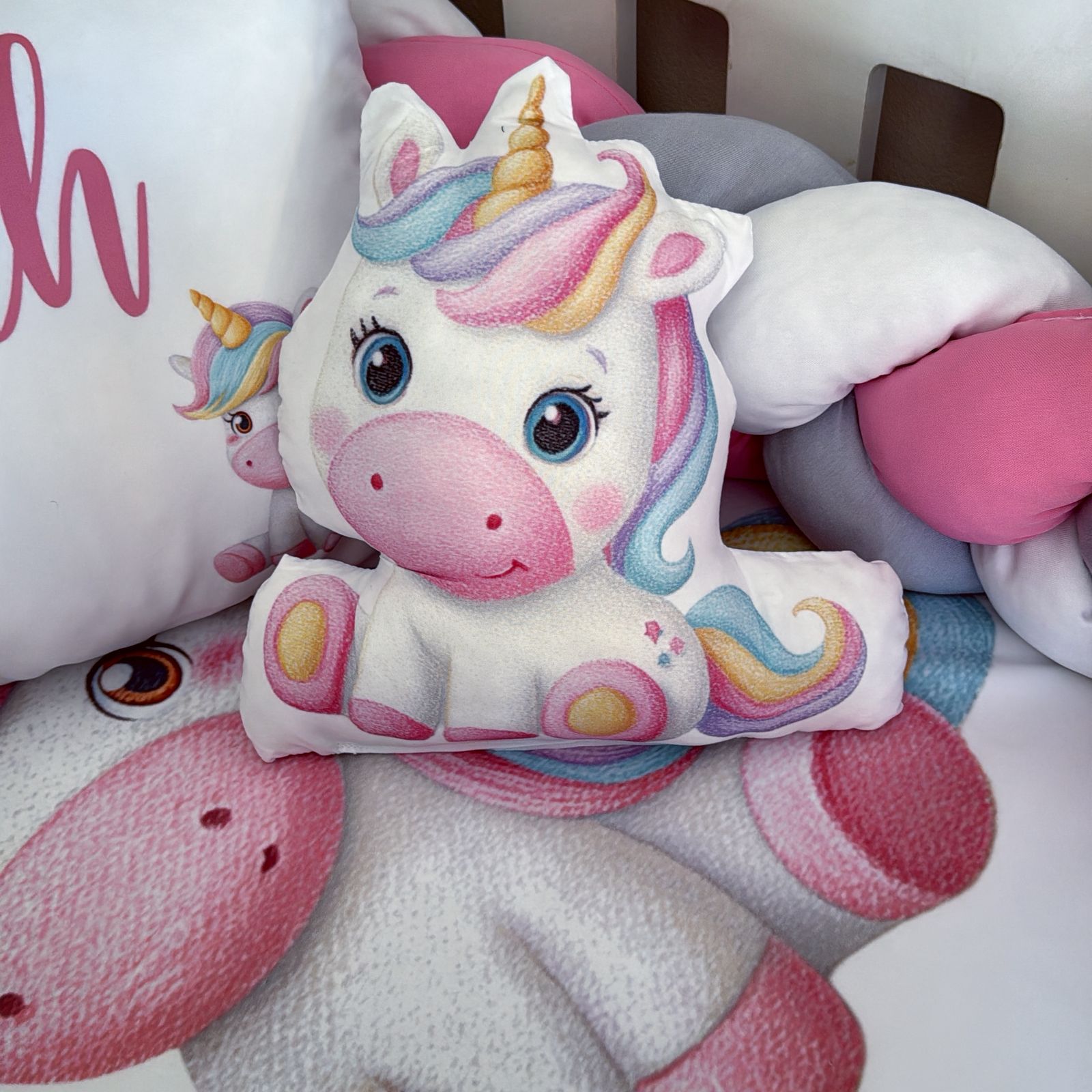 Colorful unicorn plush toy among other soft toys on a white surface