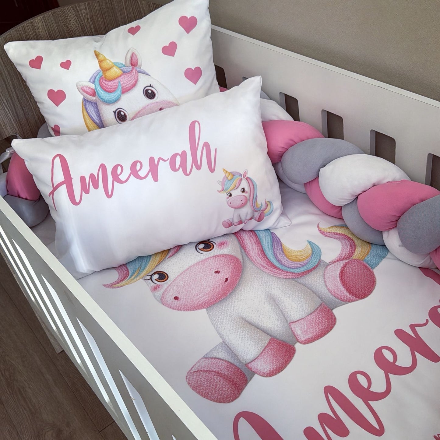 Children's bedding set with unicorn design and personalized name on a crib.