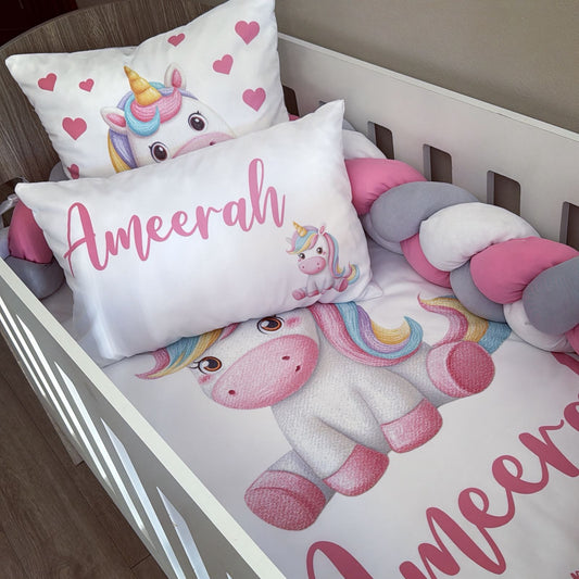 Children's bedding set with unicorn design and personalized name on a crib.