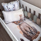 A baby crib bedding set featuring a printed cheetah on the fitted sheet and matching elephant pillowcase, styled inside a white wooden crib with a soft cushion bumper. | All Nursery Sets | Baby Bedding Sets South Africa | Soft Spot Kids | South Africa